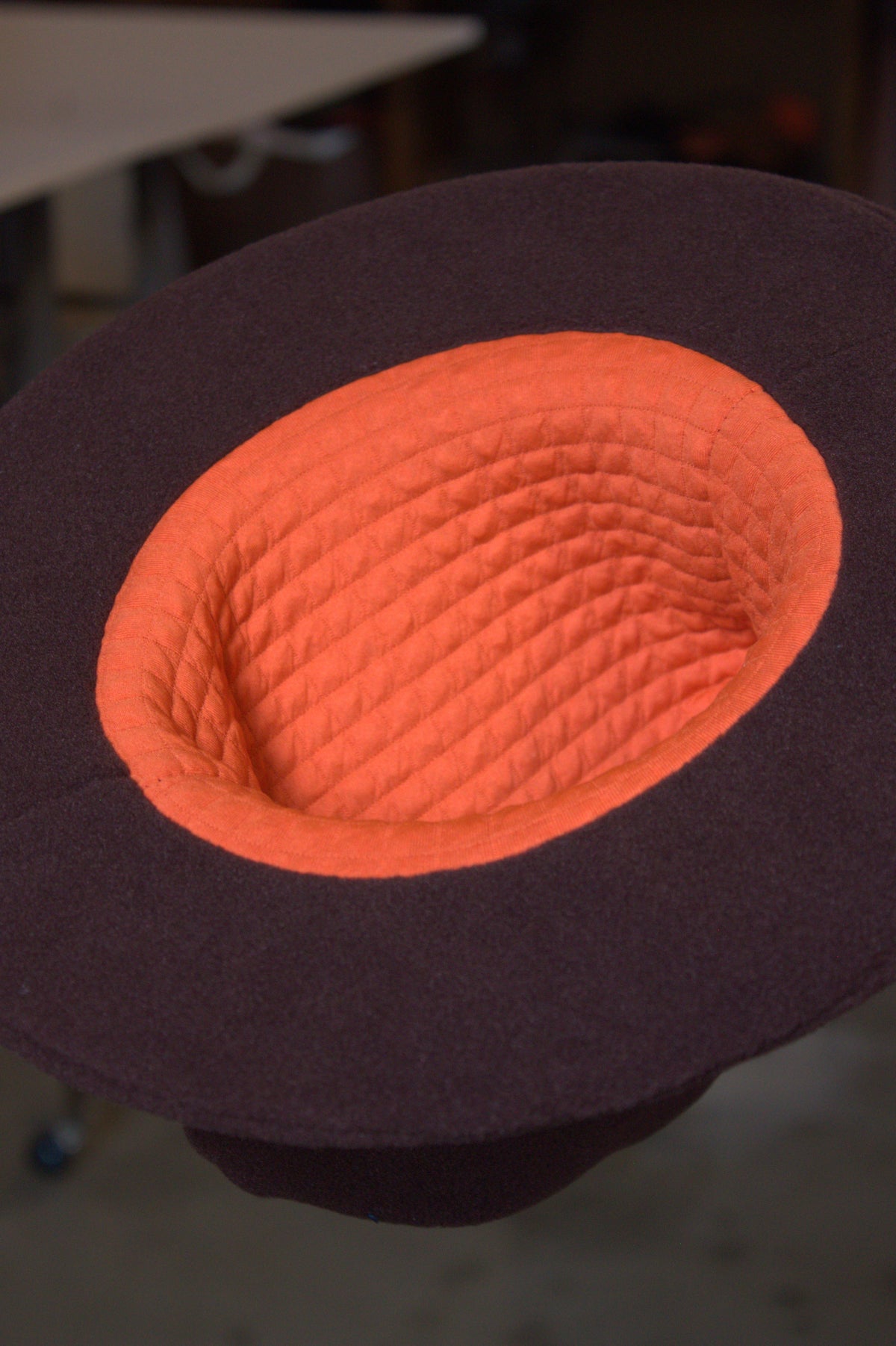 A close-up of a Howley brimmed hat viewed from above, showing a bright orange quilted inner crown lining.
