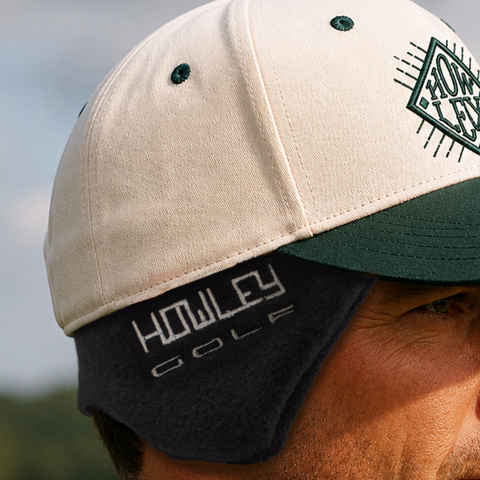Close-up of a person wearing a golf cap with 'Howley' branding outdoors.