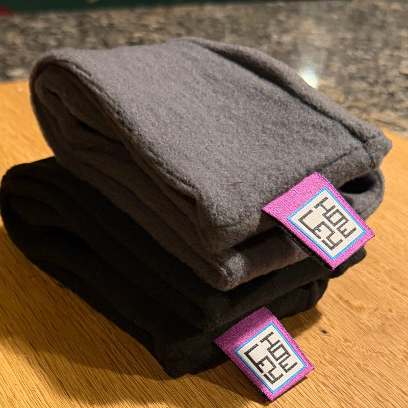 Stack of gray skullcap hats with size tags on a wooden surface