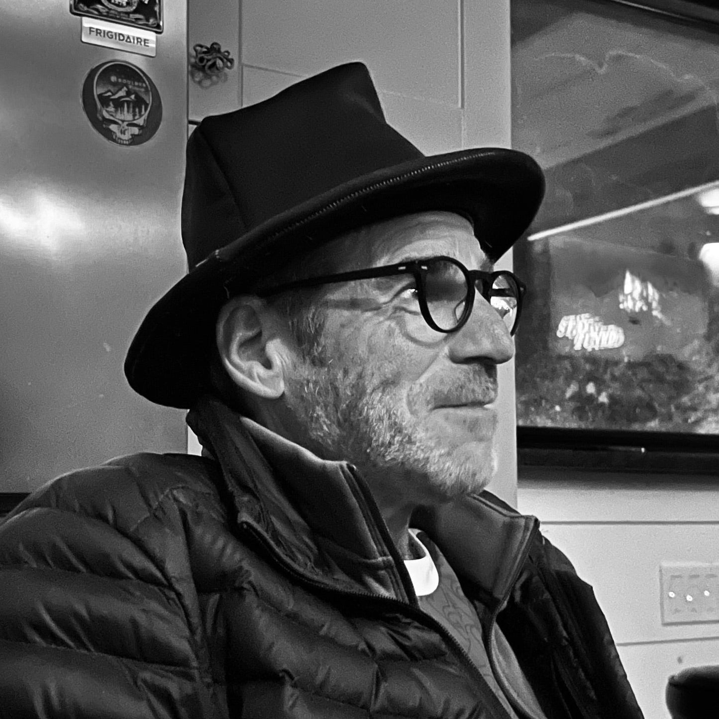 Man wearing a black howley USA hat and puffer jacket in a vehicle interior.