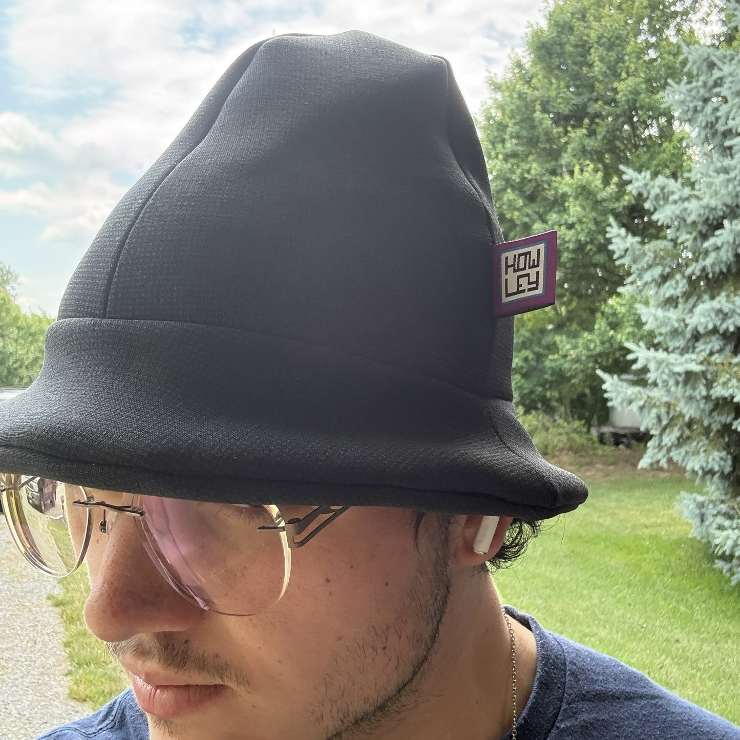 Person wearing a black the edison hat with a logo outdoors on a sunny day